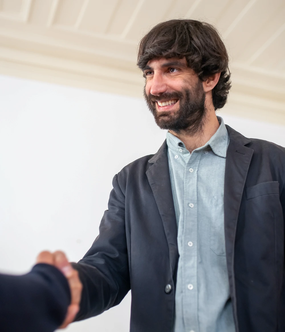 A man smiling as he shakes hands with another person