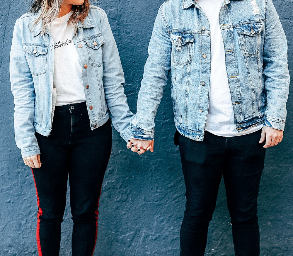 A couple in jeans jackets holding hands